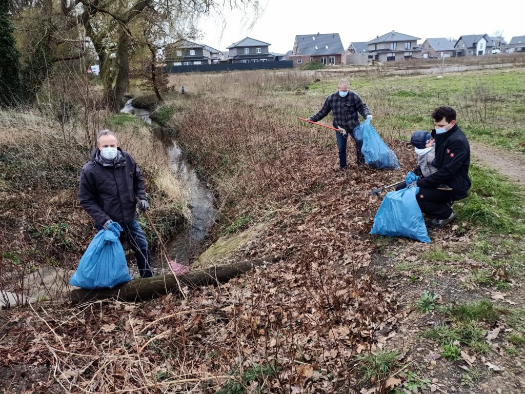 Im Umfeld des Mühlenbachs sammeln (von links) Thomas Deters, Andreas Lucht und Sergej Belz (mit Sohn Jan) Müll in blauen Plastiksäcken.