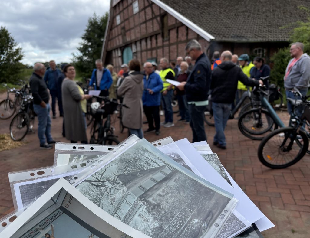 Im Vordergrund einige historische Fotos, im Hintergrund Personen und Räder vor einem Fachwerkgebäude.