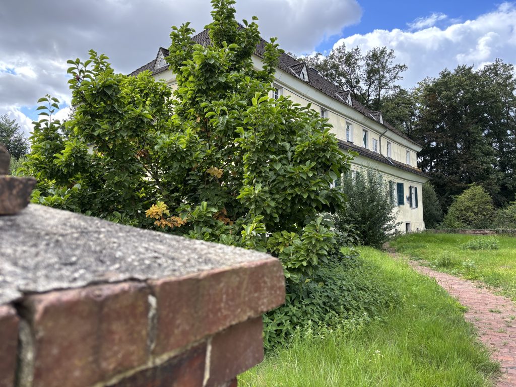 Blick auf ein weiß getünchtes, altes Gutwohnhaus.