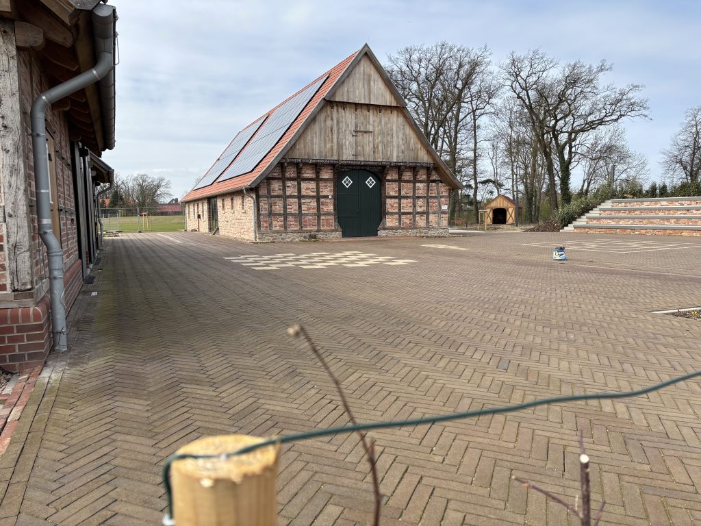 Ein neu errichtetes Fachwerkgebäude, davor ein gepflasterter Hof.